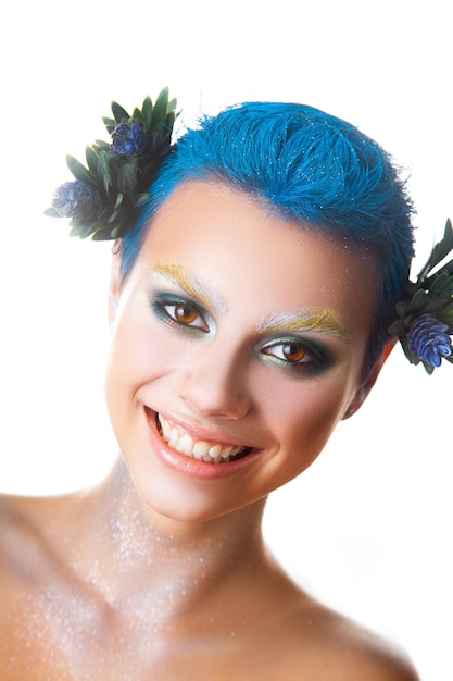 Ragazza divertente con trucco multicolore e breve acconciatura blu sorridente studio shot isolato