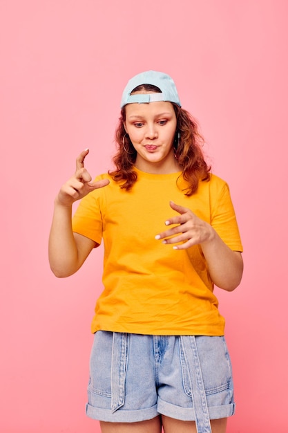 Ragazza divertente con una maglietta gialla e un berretto blu che posano emozioni Stile di vita inalterato