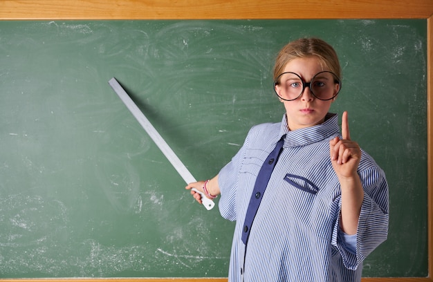 Ragazza divertente del bambino al costume dell&#39;insegnante della scuola