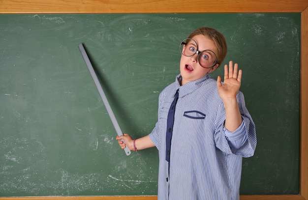 Ragazza divertente del bambino al costume dell&#39;insegnante della scuola