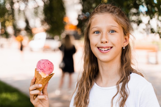 Ragazza divertente del bambino che mangia il cono gelato nella tazza della cialda Pubblicità creativa per il chiosco e il negozio del gelato