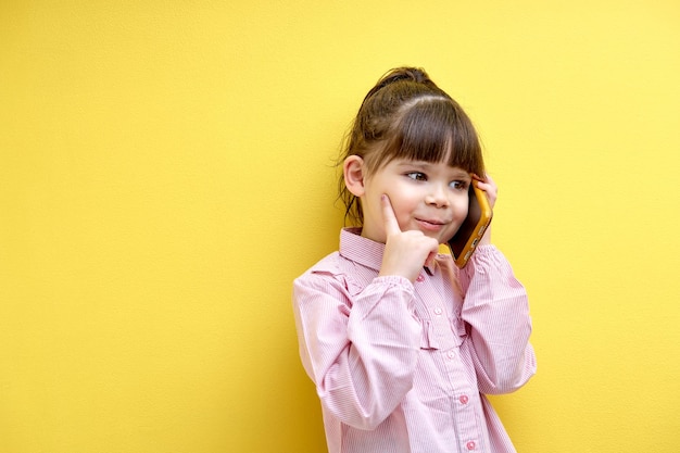 Ragazza divertente del bambino che parla al telefono con qualcuno che pensa ragazzo caucasico che guarda al lato concentrato i...