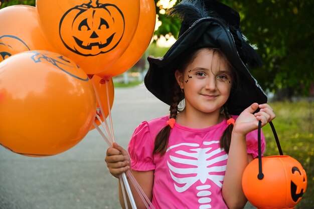 Ragazza divertente del bambino di Halloween con il trucco sul viso in costumi di carnevale all'aperto.