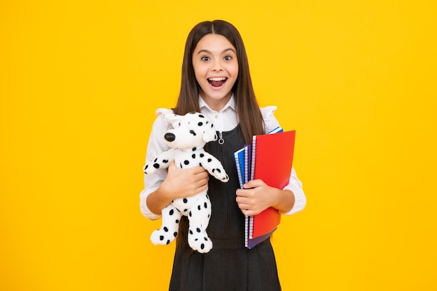 Ragazza divertente della scuola con il giocattolo isolato su sfondo giallo Infanzia felice e educazione dei bambini Felice studentessa emozioni positive e sorridenti