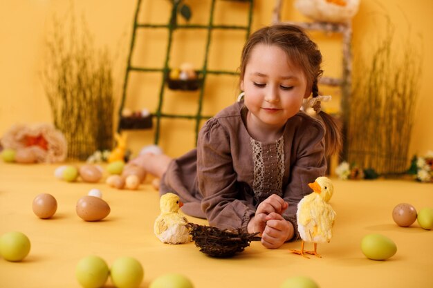 Ragazza divertente felice che gioca con le uova di Pasqua e la decorazione tradizionale di pasqua del pulcino nello stile rurale
