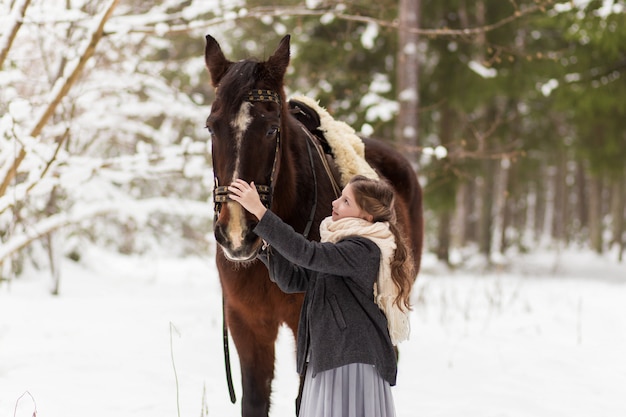 ragazza e cavallo marrone in inverno in natura