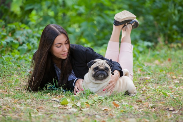 ragazza e il suo amico a quattro zampe pug per una passeggiata. Gli amici giacciono a terra.