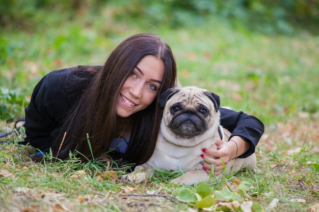 ragazza e il suo amico a quattro zampe pug per una passeggiata. Gli amici giacciono a terra.