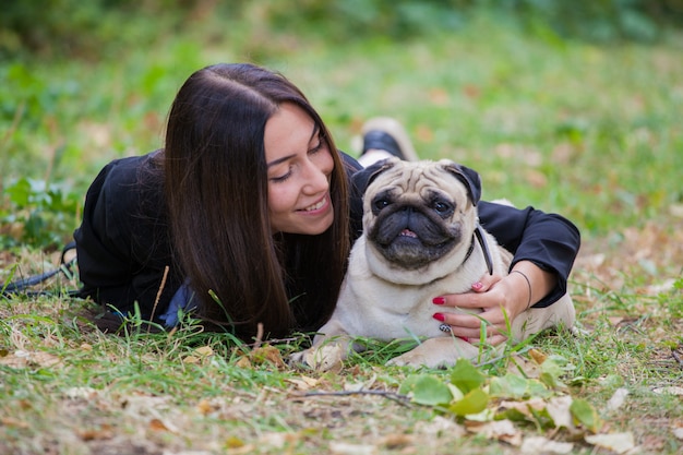 ragazza e il suo amico a quattro zampe pug per una passeggiata. Gli amici giacciono a terra.