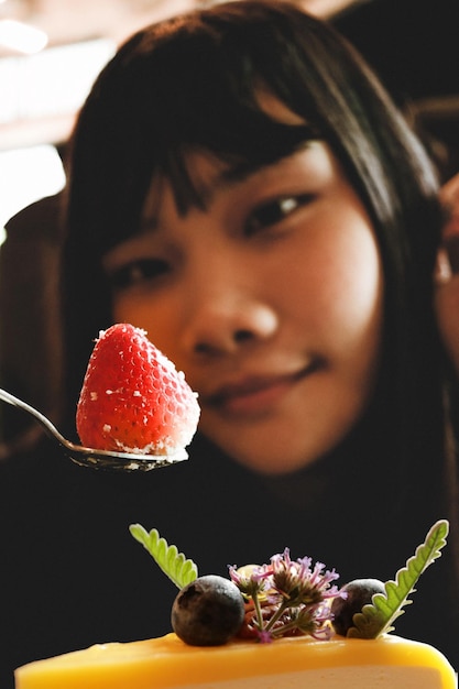 Ragazza e la sua fragola sul cucchiaio