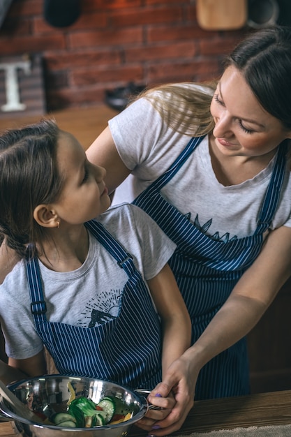 Ragazza e madre che cucinano insalata