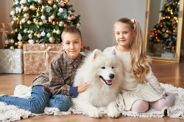 ragazza e ragazzo con cane samoiedo a natale