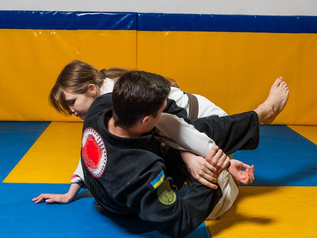 Ragazza e ragazzo praticano il jiu jitsu brasiliano in palestra