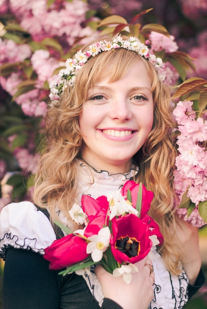 Ragazza e sakura nel parco. Donna carina con fiori