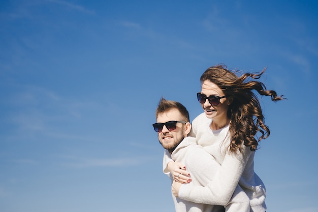 Ragazza e tipo felici che corrono e che abbracciano in volo contro il cielo, concetto di storia d'amore di viaggio, fuoco selettivo