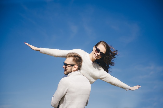 Ragazza e tipo felici che corrono e che abbracciano in volo contro il cielo, concetto di storia d'amore di viaggio, fuoco selettivo