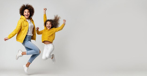 Ragazza eccitata che celebra il successo e salta in alto sullo sfondo bianco giallo