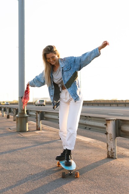 Ragazza elegante e felice che prova a guidare un longboard