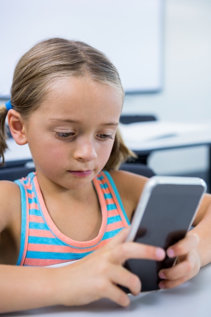 Ragazza elementare che utilizza telefono cellulare nell'aula