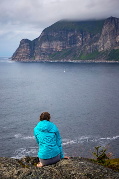 ragazza escursionista si erge su una scogliera ammirando il paesaggio dell'isola di senja nel nord della Norvegia