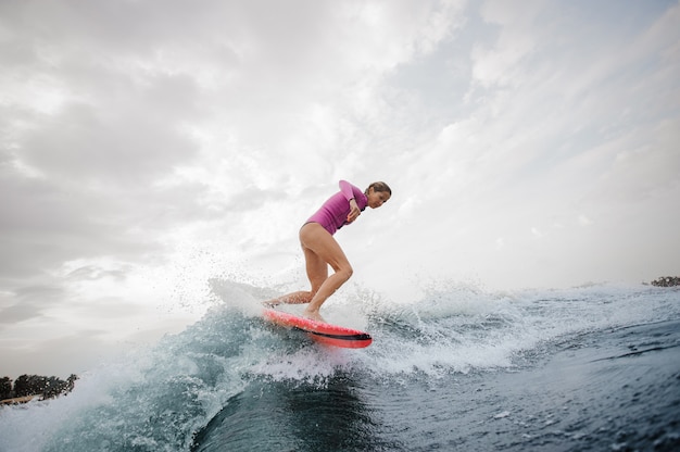 Ragazza esile attiva che guida sul wakeboard arancio