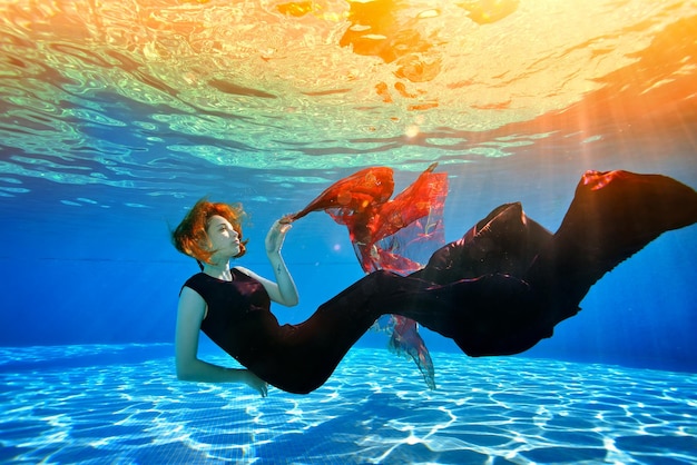 Ragazza fantastica con i capelli rossi in posa sott'acqua in piscina