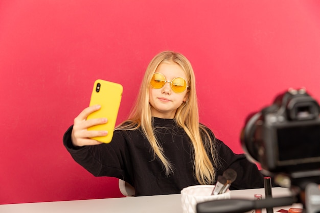 Ragazza felice a casa che parla davanti alla telecamera per vlog. Ragazzino che lavora come blogger, registrando video tutorial per Internet.