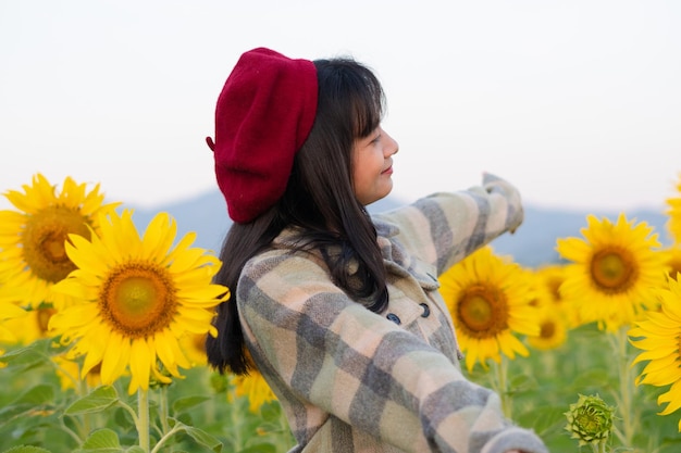 Ragazza felice al giacimento del girasole con cielo blu