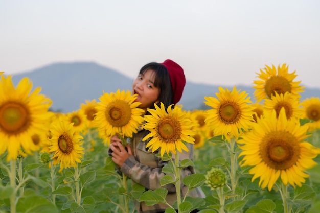 Ragazza felice al giacimento del girasole con cielo blu