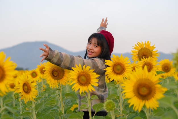 Ragazza felice al giacimento del girasole con cielo blu