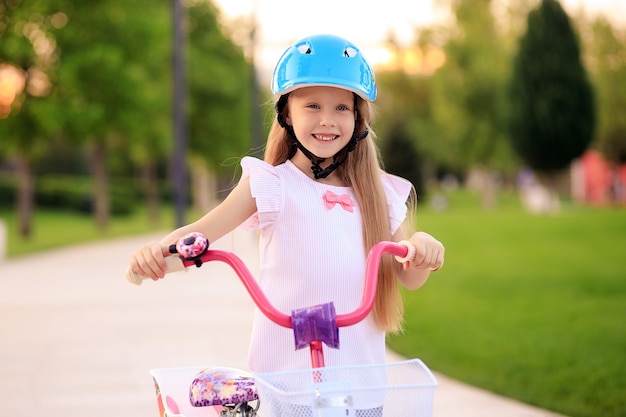 Ragazza felice bambino allegro in bicicletta nel parco