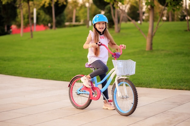 Ragazza felice bambino allegro in bicicletta nel parco