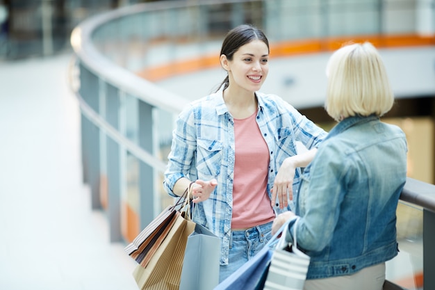 Ragazza felice che ascolta l'amico in corridoio del centro commerciale