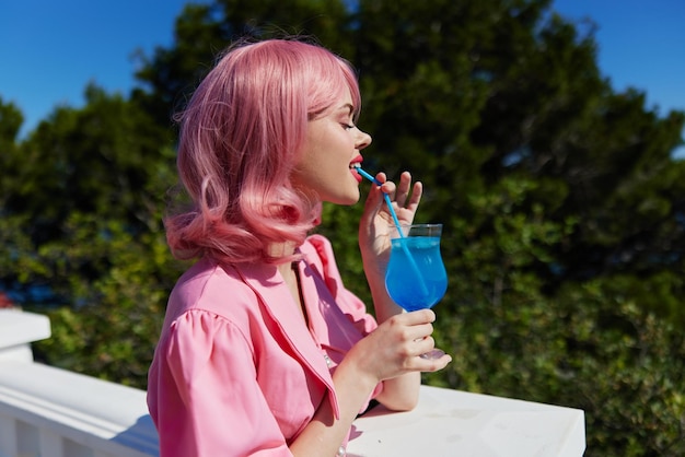 Ragazza felice che beve un cocktail sulla terrazza immutata foto di alta qualità