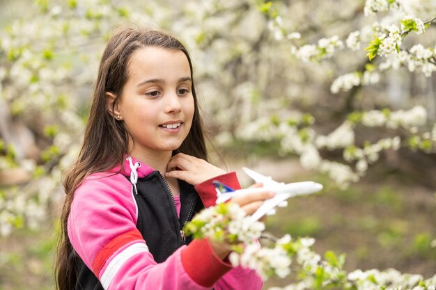 Ragazza felice che gioca con l'aereo giocattolo in giardino