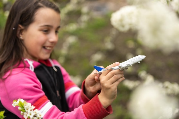 Ragazza felice che gioca con l'aereo giocattolo in giardino