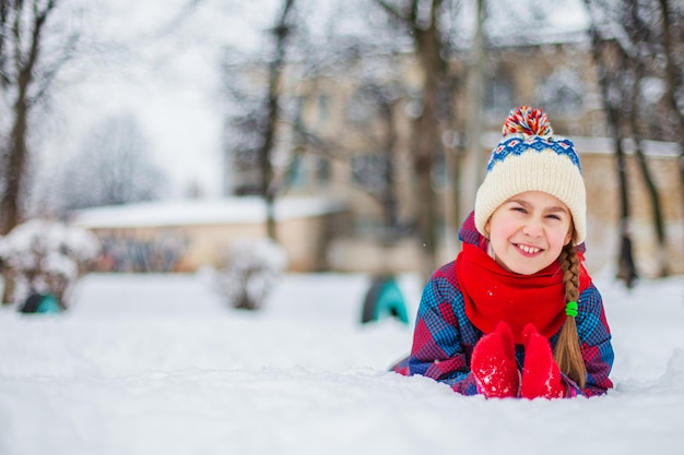 Ragazza felice che gioca con la neve in una passeggiata invernale nevosa facendo palle di neve nel parco