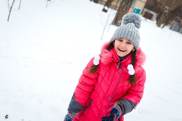 Ragazza felice che gioca in un parco giochi al giorno gelido di inverno.