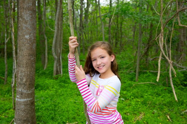 Ragazza felice che gioca nella giungla di Forest Park con la liana