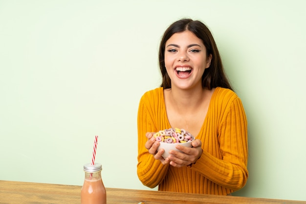 Ragazza felice che mangia prima colazione con la ciotola di cereali