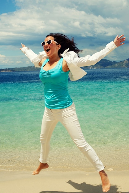 Ragazza felice che salta sulla spiaggia, vacanze estive