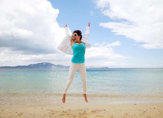 Ragazza felice che salta sulla spiaggia