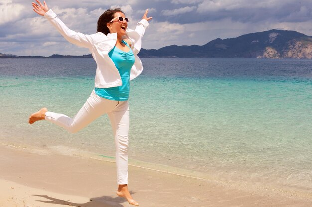 Ragazza felice che salta sulla spiaggia