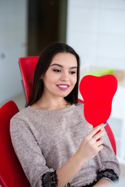 Ragazza felice che si guarda allo specchio in un sorriso in odontoiatria