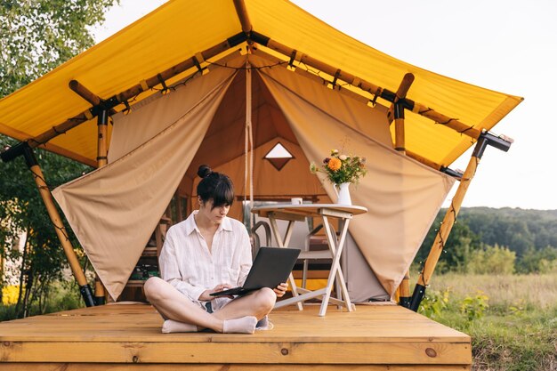 Ragazza felice che si rilassa in vacanza in campeggio giovane donna seduta in una tenda da campeggio giovane modella caucasica donna che legge testo e lavora sul quaderno