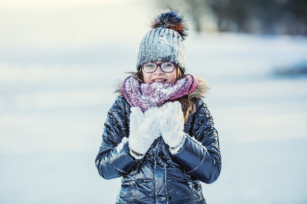 Ragazza felice che soffia la neve nel gelido parco invernale o all'aperto Ragazza e clima freddo invernale