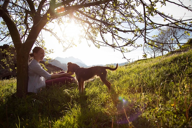 Ragazza felice che sorride al suo cane che le dà una palla gialla con cui giocare