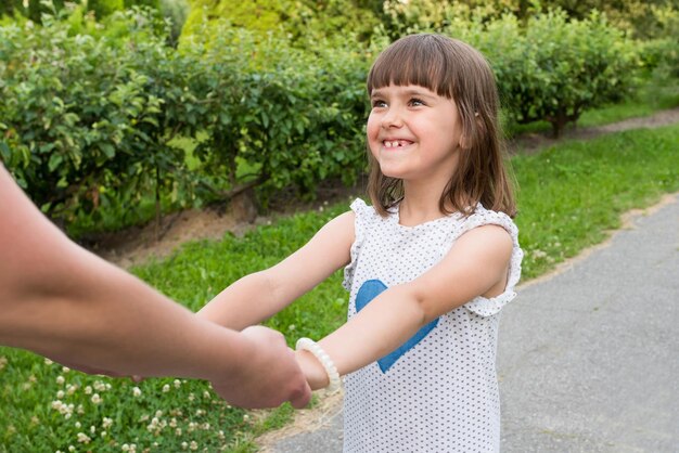 Ragazza felice che tiene le mani della madre all'aperto nel giardino