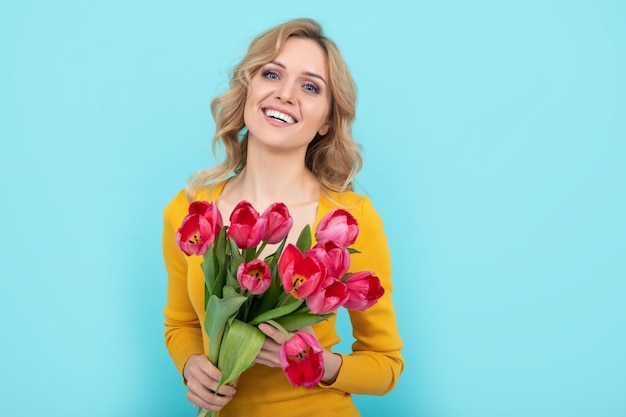 Ragazza felice con bouquet di tulipani su sfondo blu