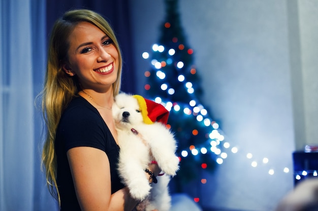 Ragazza felice con cane husky samoiedo nelle decorazioni natalizie